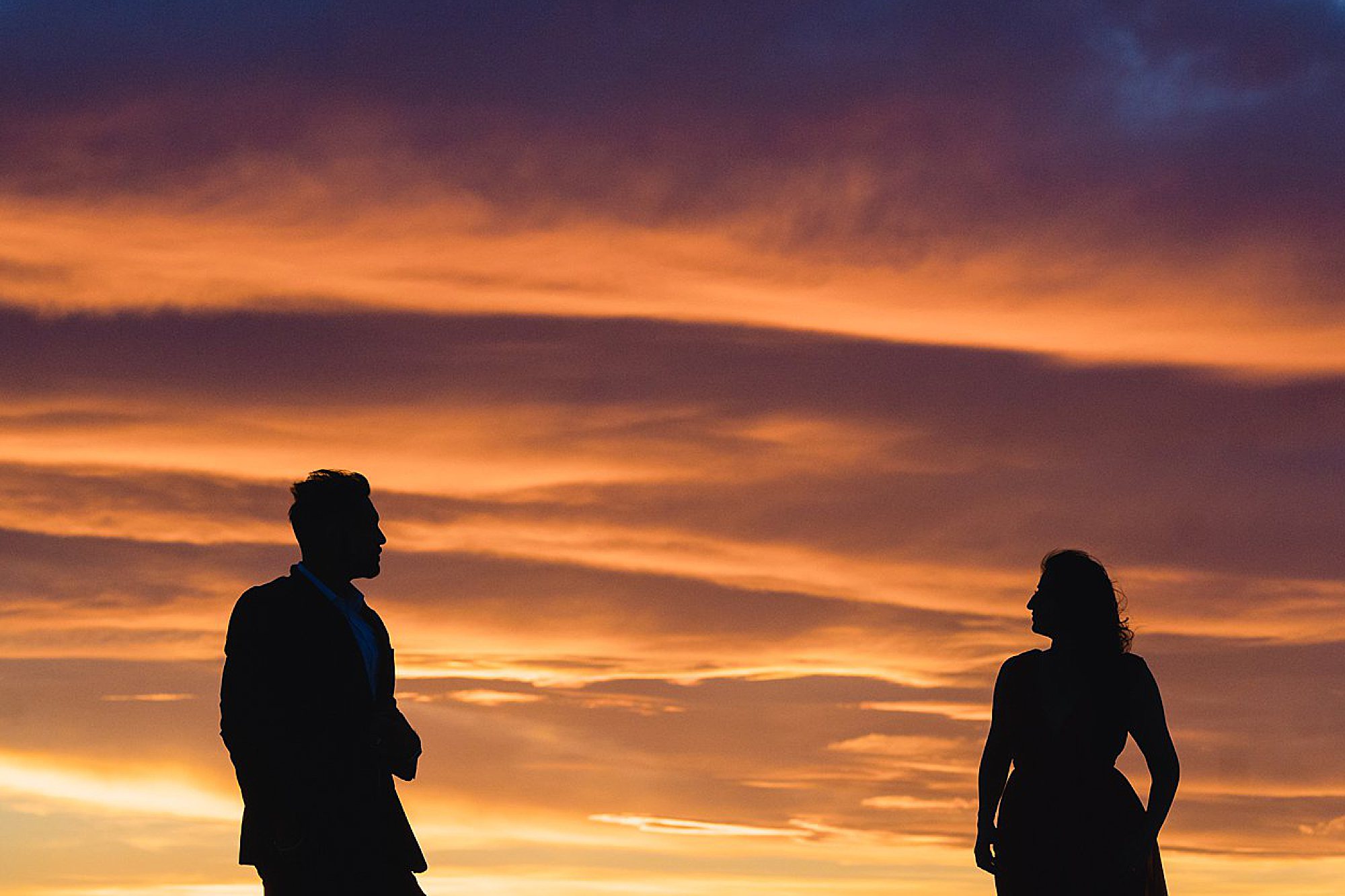 silhouttes against orange sunset clouds 